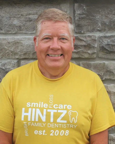 Dr. Scott Hansen, DDS, smiling in a yellow Hintz Family Dentistry t-shirt